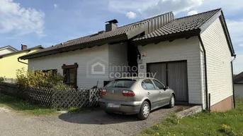 Vorderansicht des Einfamilienhauses mit Garage und Stellplatz auf dem Kiesweg unter blauem Himmel.
