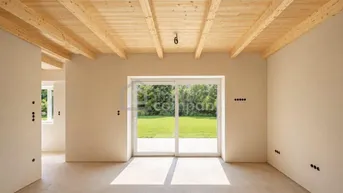 Heller Wohnraum mit Holzbalkendecke und großer Schiebetür zum Garten.