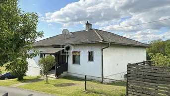 Einfamilienhaus mit weißer Fassade, Satteldach und gepflegtem Vorgarten in ländlicher Umgebung.
