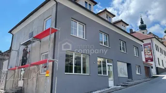 Gebäudeansicht mit grauer Fassade und Gerüst, das auf laufende Renovierungsarbeiten hinweist.