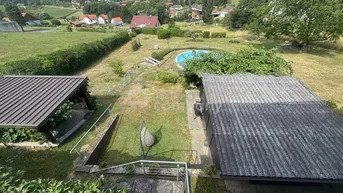 Weitläufiger Gartenbereich mit Pool, Liegewiese und Blick auf die umliegende Landschaft.