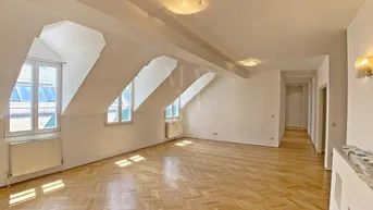 Helles und geräumiges Wohnzimmer mit Fischgrätparkett, Dachschrägen und mehreren Gaubenfenstern.
