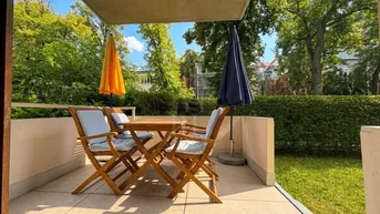 Möblierte Terrasse mit Sitzgelegenheiten und Sonnenschirmen, umgeben von grünen Bäumen.