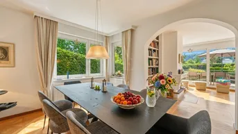 Heller Essbereich mit großem Holztisch, bequemen Stühlen und Blick ins Grüne, verbunden mit dem Wohnzimmer.