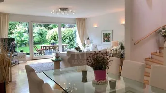 Heller Wohn- und Essbereich mit großen Glasfronten, die zum grünen Garten und einer Terrasse führen.