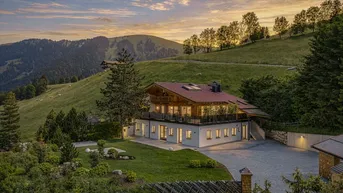 Luxuriöses Chalet in den Bergen bei Sonnenuntergang mit weitläufigem Grundstück und Panoramablick.