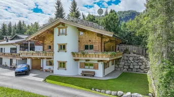 Großzügiges Chalet-Haus mit Holzfassade, Balkonen und umgebender Natur.