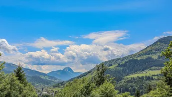 Malerischer Blick auf die Alpenlandschaft mit grünen Hügeln und blauem Himmel.