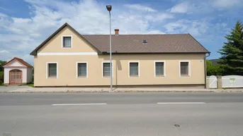 Traditionelles Einfamilienhaus mit beiger Fassade und Satteldach, direkt an einer Straße gelegen.
