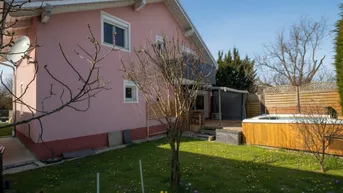 Ansicht des Hauses von der Seite mit Garten, Rasenfläche und integriertem Whirlpool auf einem Holzdeck.