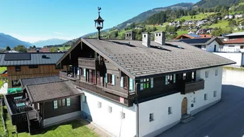 Traditionelles Haus im alpinen Stil mit Holzbalkonen und Blick auf die umliegenden Berge.