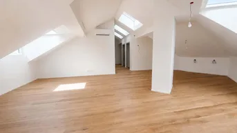 Heller Dachgeschossraum mit Holzboden, Dachfenstern und Klimaanlage, bereit für den Ausbau.