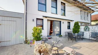 Geräumige gepflasterte Terrasse hinter dem Haus mit Gartenmöbeln und Zugang zum Innenbereich.