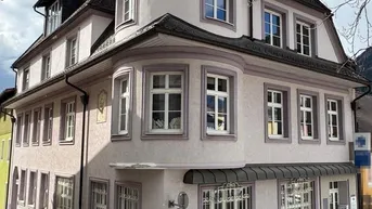 Historisches Gebäude mit markanter Architektur und runden Erkern in einer städtischen Umgebung.