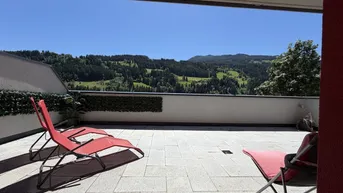 Geräumige Sonnenterrasse mit Liegestühlen und weitem Blick auf die umliegende Berglandschaft.