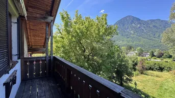 Traditioneller Holzbalkon mit geschnitztem Geländer und weitem Blick auf die umliegende Berglandschaft.