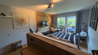 Gemütliches Schlafzimmer mit Holzakzenten, Balkonzugang und Blick ins Grüne.