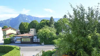Panoramablick auf die Berge und grüne Umgebung mit einer Straße im Vordergrund.