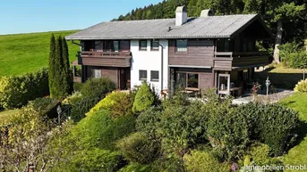 Großzügiges Einfamilienhaus mit Holzfassade und gepflegtem Garten in ländlicher Umgebung.