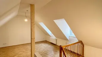 Helles Dachgeschosszimmer mit Holzboden, sichtbarem Balken und Dachfenstern.