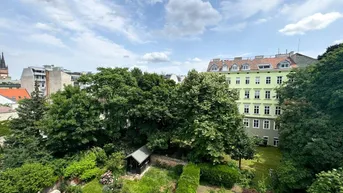 Weitläufiger grüner Gartenbereich mit altem Baumbestand und einem Gartenhaus, umgeben von Stadtgebäuden.