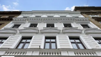 Klassische Altbaufassade mit vielen Fenstern und dekorativen Elementen von unten gesehen.