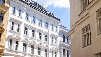 Elegante weiße Fassade eines historischen Gebäudes mit vielen Fenstern.