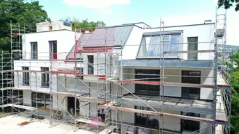 Neubauwohnungen im Bau mit Gerüst und Blick auf die Umgebung.