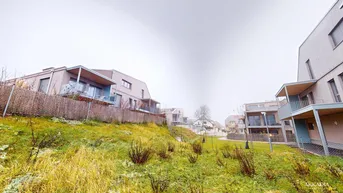 Moderne Wohnsiedlung in Hanglage mit viel Grünfläche und ähnlichen Gebäuden in der Umgebung.