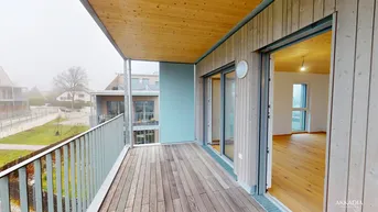 Geräumiger Balkon mit Holzboden und Blick auf die umliegende Wohnsiedlung.