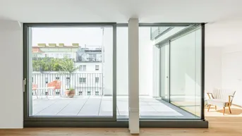 Heller Wohnraum mit großen Schiebetüren und Zugang zu einer geräumigen Terrasse.