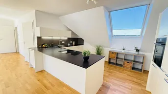Moderne offene Küche mit Kücheninsel, Holzboden und Dachfenster in einem hellen Dachgeschoss.