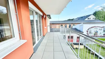 Geräumiger Balkon mit Fliesenboden und orangefarbener Fassade, bietet einen Blick auf die Umgebung.