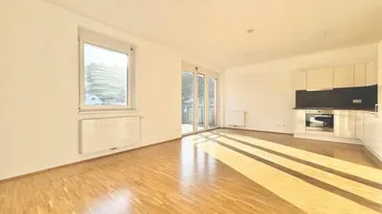 Heller Wohnbereich mit integrierter Küchenzeile, Parkettboden und viel Tageslicht.