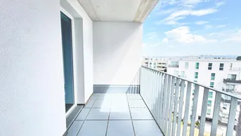 Heller Balkon mit Fliesenboden und Blick auf die umliegenden Gebäude und den Himmel.