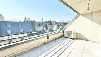 Geräumige Dachterrasse mit Fliesenboden, Blick über die Dächer der Stadt und viel Sonnenlicht.