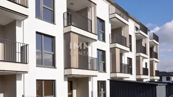 Moderne Wohnanlage mit weißen Fassaden, Balkonen und klarem Himmel.