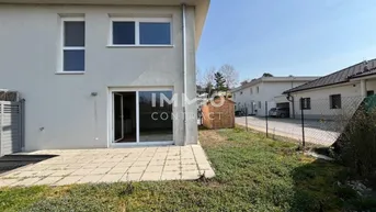 Rückseite des Neubaus mit kleiner Terrasse, Gartenbereich und Zugang ins Grüne.