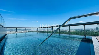 Exklusiver Dachterrassenpool mit glitzerndem Wasser, Panoramablick über die Stadt und weitem Horizont unter blauem Himmel.