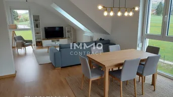 Helles, modern eingerichtetes Wohn-Esszimmer mit Dachschrägen, großen Fenstern und Blick ins Grüne.