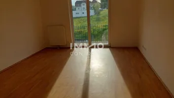 Heller Wohnraum mit Laminatboden und großem Fenster mit Zugang zu einem französischen Balkon.