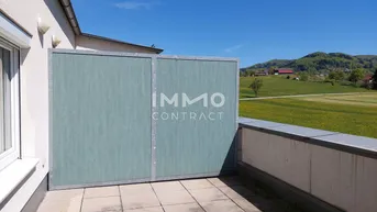 Geräumige Terrasse mit Fliesenboden, Sichtschutz und weitem Blick über die grüne Landschaft.