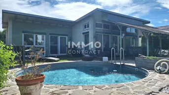 Modernes Haus mit privatem Pool und Gartenbereich unter blauem Himmel.
