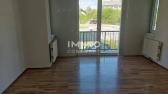 Helles, leeres Wohnzimmer mit Laminatboden, Heizkörpern und Zugang zu einem französischen Balkon.