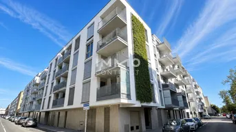 Modernes Wohngebäude mit weißer Fassade, Balkonen und vertikaler Begrünung an der Ecke.