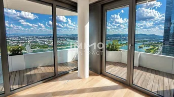 Helles Zimmer mit Holzboden und raumhohen Fenstern, die einen weiten Stadt- und Flussblick bieten.