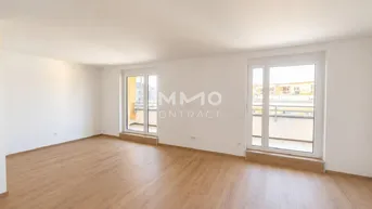 Heller Wohnraum mit Laminatboden und zwei Fenstertüren, die Zugang zu einem französischen Balkon bieten.
