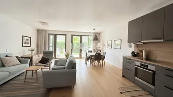 Heller offener Wohn-Essbereich mit integrierter Küche, Holzboden und Zugang zur Terrasse.