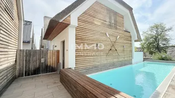 Modernes Haus mit Reetdach, Holzfassade und privatem Poolbereich mit gefliester Terrasse.