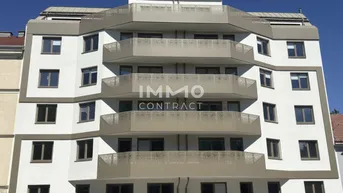 Modernes Mehrfamilienhaus mit weißer Fassade und mehreren Balkonen unter blauem Himmel.